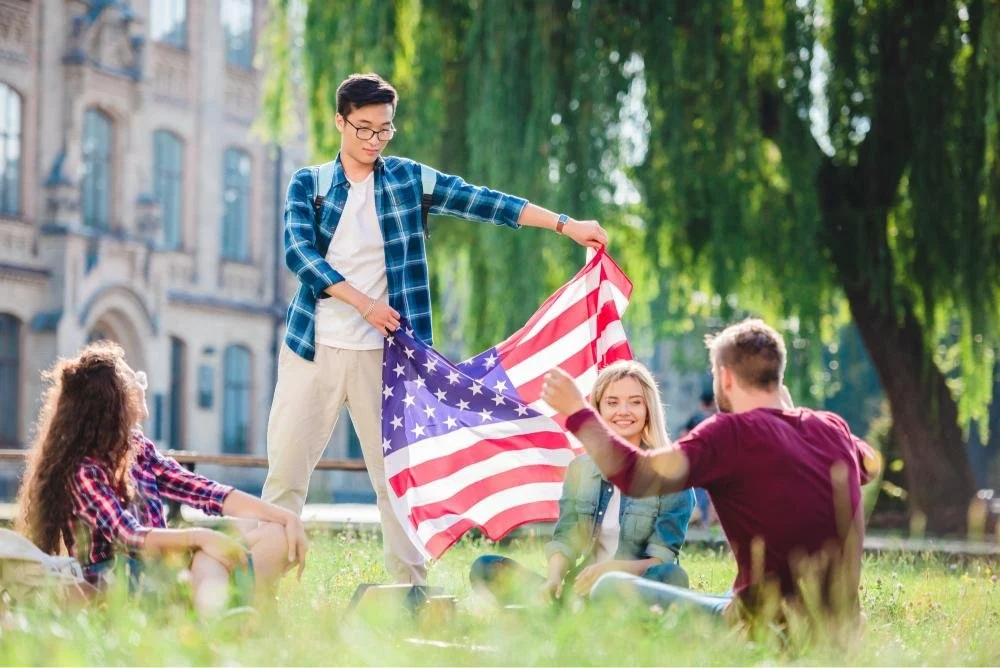 Multicultural students with american flag in summer park